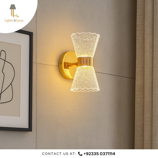 Decorative wall sconce with gold finish and textured glass shade on a neutral wall.