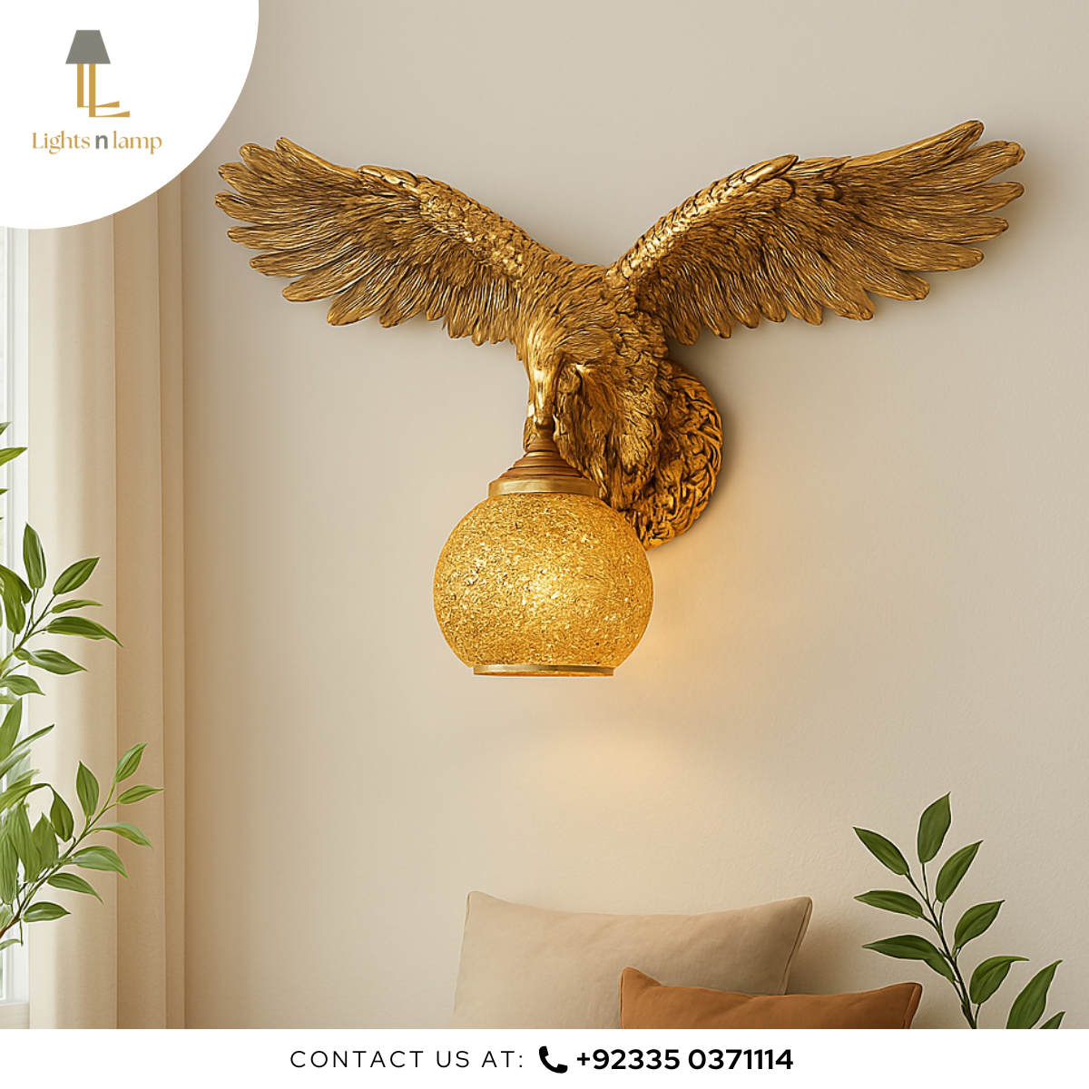 Gold eagle wall light fixture on a beige wall with plants and a pillow.