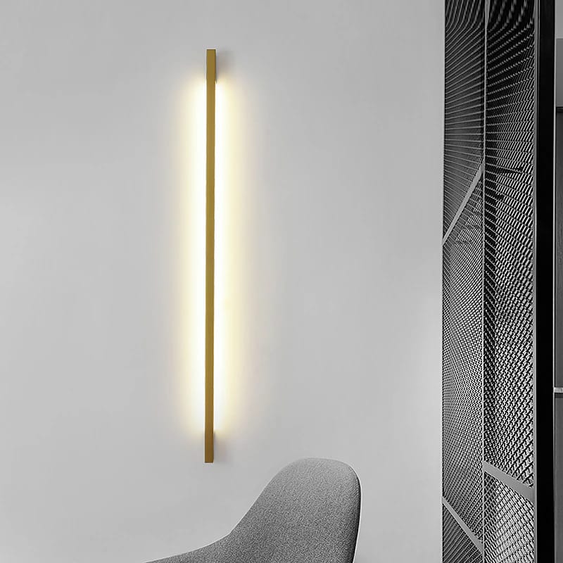 Modern wall-mounted light fixture on a gray wall with a chair in the foreground.
