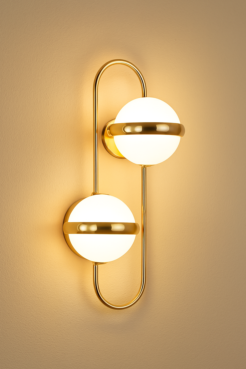 Gold wall sconce with two white globe lights on a beige wall.