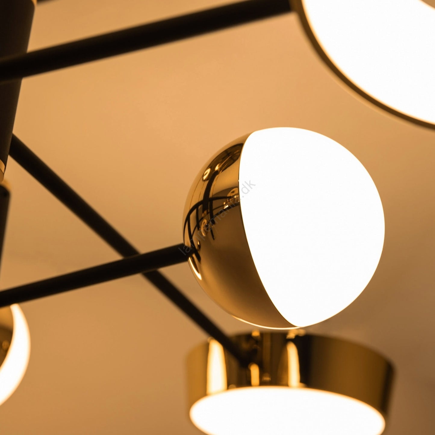 Close-up of a modern ceiling light fixture with gold finish and white lampshades.