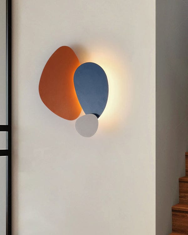 Modern wall light fixture with orange, blue, and white components on a neutral wall.