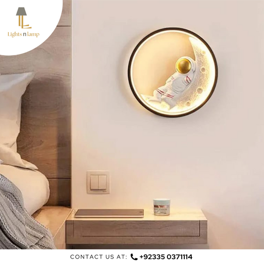 Round wall light fixture on a bedroom wall with a bed and nightstand in the background.
