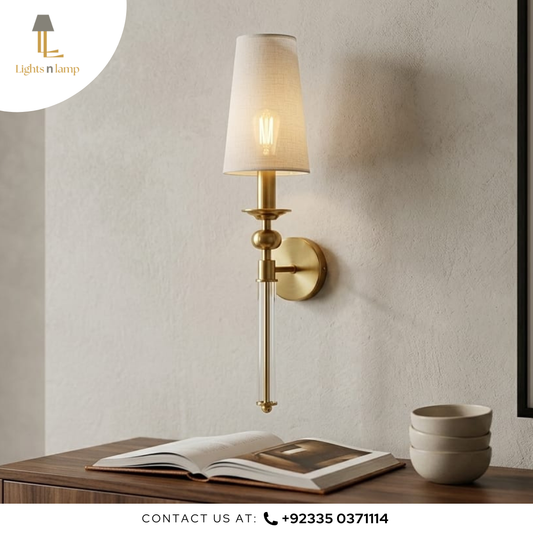 Wall-mounted lamp with a beige shade on a neutral wall, next to an open book and a stack of bowls.
