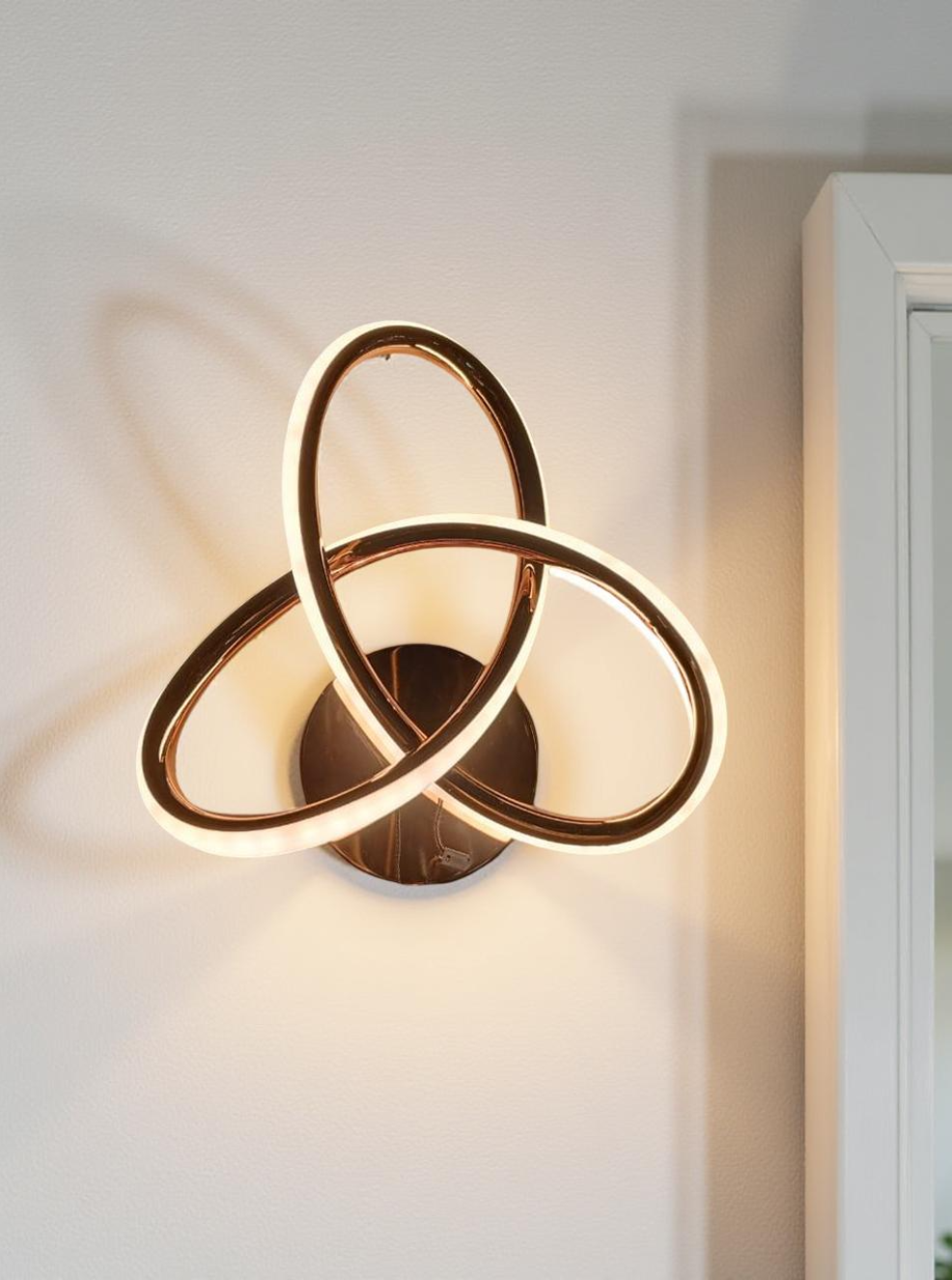 Modern wall light fixture with interlocking circular design on a white wall.