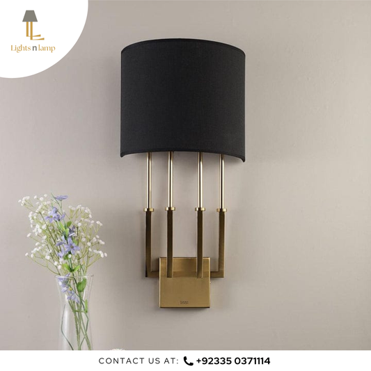 Wall-mounted lamp with black shade and gold base on a beige wall, accompanied by a vase of flowers.