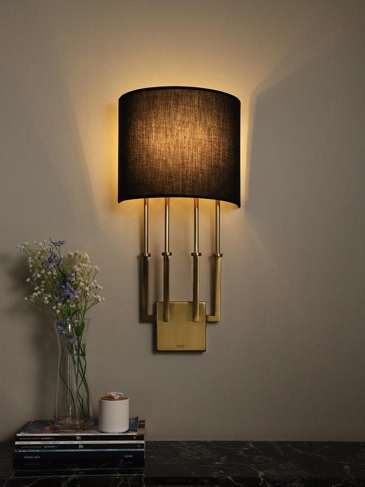 Decorative wall sconce with a black shade on a neutral wall.