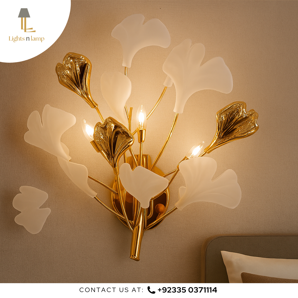 Decorative wall light fixture with gold and white leaves on a beige wall.