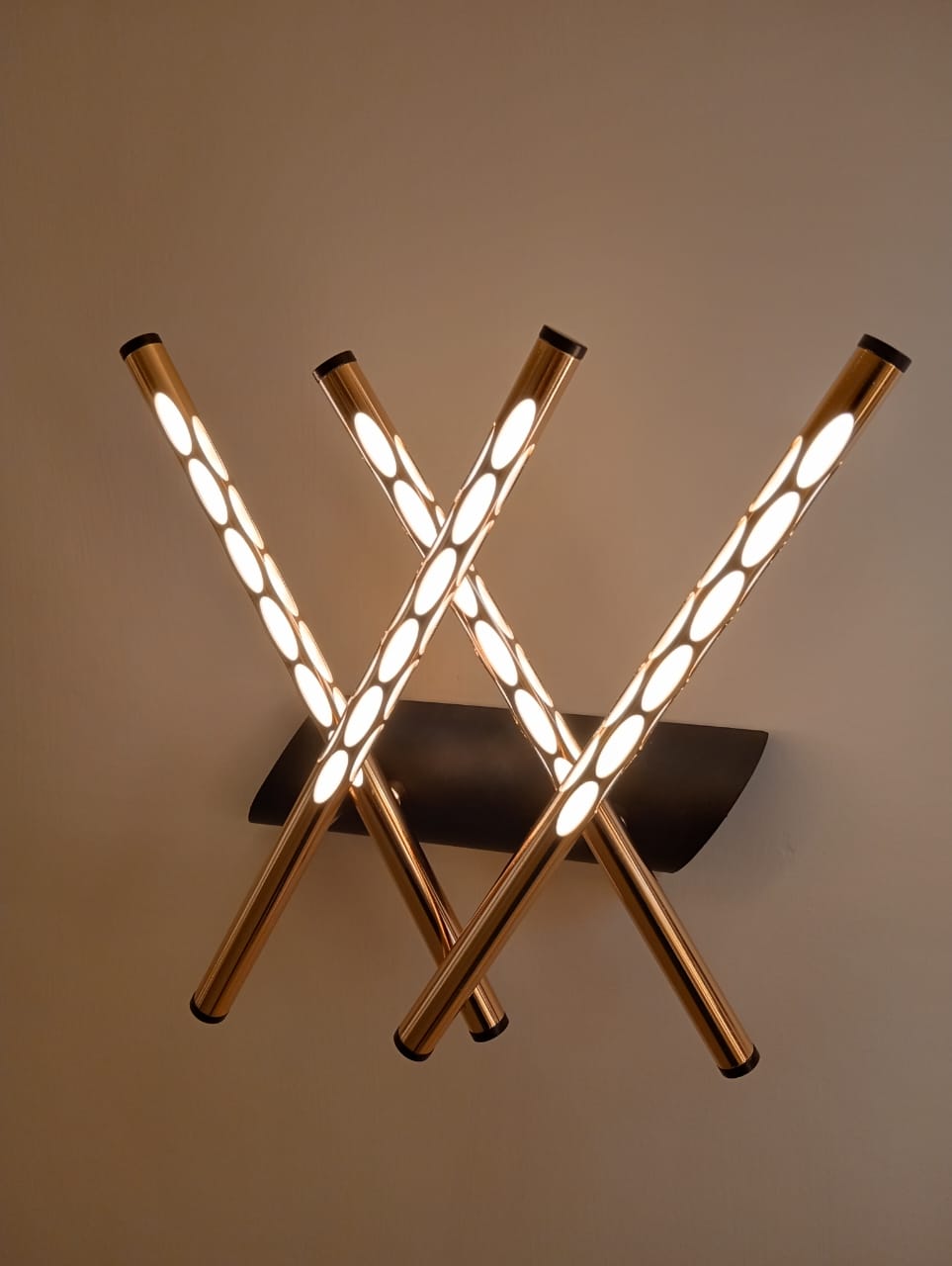 Modern ceiling light fixture with three illuminated cylindrical arms on a neutral background