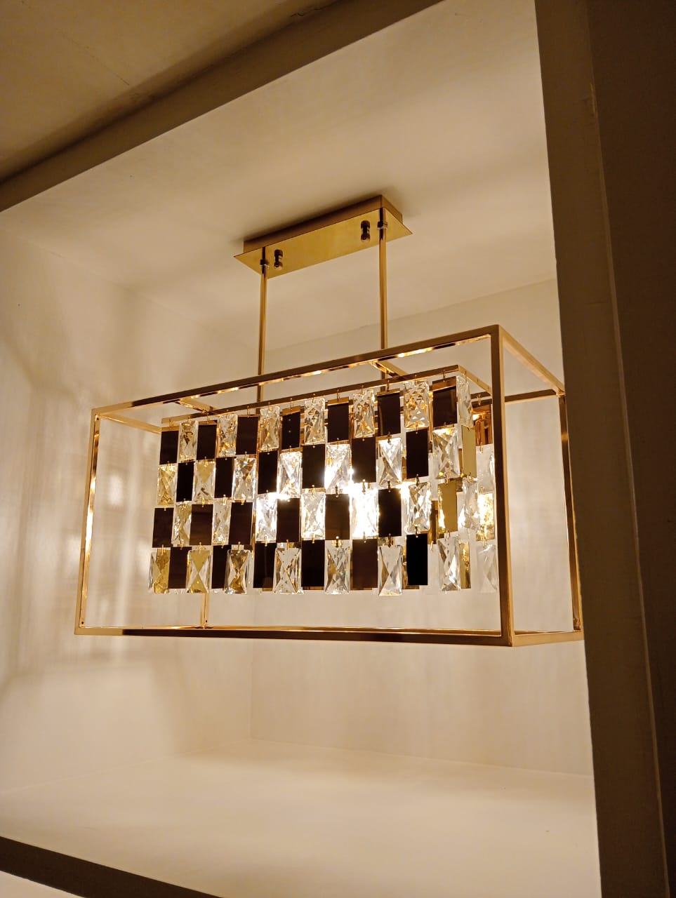 Luxury chandelier with gold frame and crystal accents on a white ceiling.