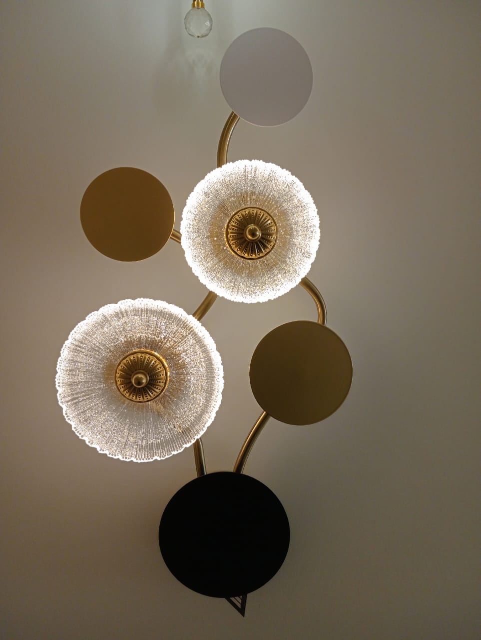 Modern chandelier with gold and black design on a neutral background
