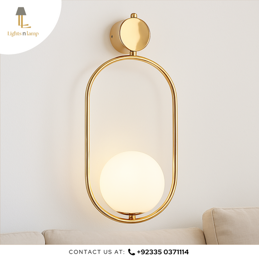 Gold wall-mounted lamp with a white light bulb on a light gray wall.