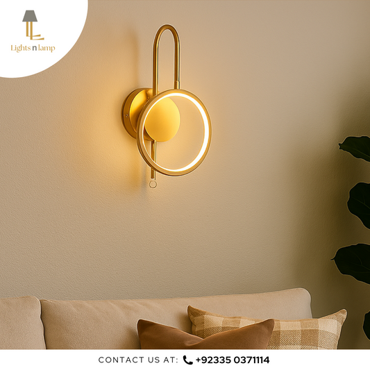 Gold wall sconce on a beige wall with a couch and pillows in the foreground.