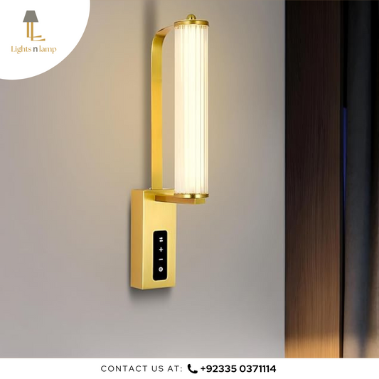 Gold wall-mounted light fixture on a gray wall with a blurred background