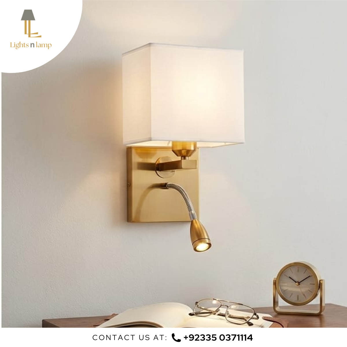 Gold wall sconce with reading light on a white wall, next to an open book and glasses.