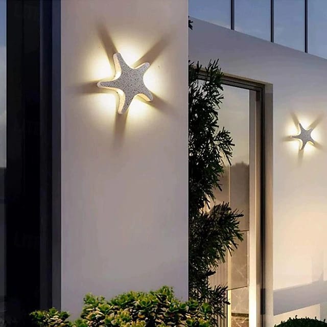 Star-shaped outdoor wall lights on a building exterior with plants.