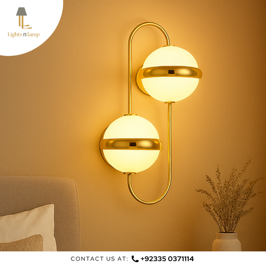 Gold wall sconce with two spherical lights on a warm-toned wall.